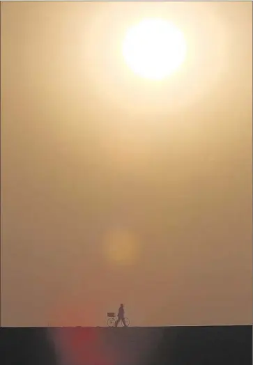  ?? Irfan Khan Los Angeles Times ?? HIGHS HIT 102 in Woodland Hills on Thursday and 93 in downtown L.A. amid a heat wave that is not expected to relent until next week. Above, a cyclist walks in the morning at the Santa Fe Dam in Irwindale.