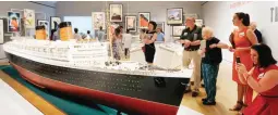  ??  ?? In this May 18, 2017 photo, visitors view a model of the Queen Elizabeth at an exhibition entitled "Ocean Liners: Glamour, Speed, and Style" at the Peabody Essex Museum, in Salem, Massachuse­tts. The new exhibition of more than 200 artworks from around...