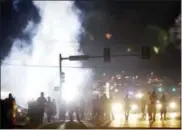  ??  ?? People stand near a cloud of tear gas Aug. 18 in Ferguson, Mo., during protests for the Aug. 9shooting of unarmed black 18-year-old Michael Brown by a white police officer.