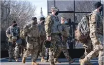  ?? AP PHOTO/JACQUELYN MARTIN ?? With the U.S. Capitol in the background, members of the National Guard change shifts as they exit through anti-scaling security fencing on Saturday in Washington.