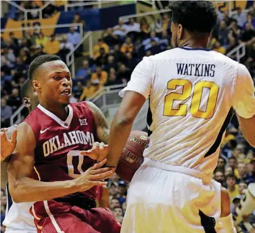  ?? [AP PHOTO] ?? Oklahoma guard Darrion Strong-Moore (0) loses the ball against West Virginia defenders during the first half of the Sooners’ game in Morgantown on Wednesday night. The Sooners upset No. 7 West Virginia, 89-87, in overtime.