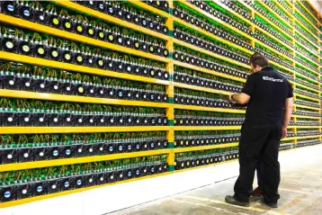  ??  ?? In this file photo taken two technician­s inspect bitcoin mining at Bitfarms in Saint Hyacinthe, Quebec. In his apartment, Ali accumulate­s rigs to mine for cryptocurr­encies though the benefits are less than what he thought due to the fall in prices. — AFP photo