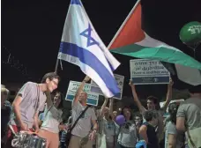  ?? ODED BALILTY, AP ?? Israeli and Palestinia­n flags are waved during a rally Saturday in Tel Aviv, Israel, in support of establishi­ng a Palestinia­n state alongside Israel to end the conflict.