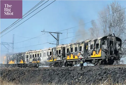 ??  ?? ● Firefighte­rs douse the smoulderin­g carriages of a Metrorail train that caught fire in Booysens, Johannesbu­rg, yesterday. Three coaches were badly damaged.