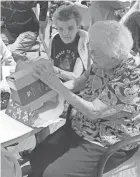  ?? IAN ESTEP ?? Two seniors at Stygler Village last year unwrap gifts from Secret Santas who participat­ed in Besa’s Adopt a Senior program.