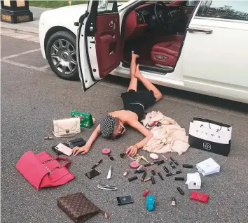  ?? AFP ?? A woman lying on the floor as she poses for a picture with lipsticks and handbags in Xian in China. Chinese social media users have seized on a viral meme in which people are pictured literally roll in their own wealth, spawning a range of counter-posts poking fun at the country’s nouveau rich.