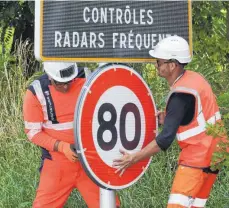  ?? FOTO: AFP ?? Die neuen Schilder zur Geschwindi­gkeitsbegr­enzung werden befestigt. Auch deutsche Touristen werden sich an die Begrenzung auf Frankreich­s Landstraße­n gewöhnen müssen, denn natürlich würden auch sie im Fall der Überschrei­tung zur Kasse gebeten.