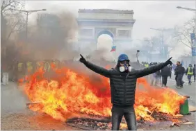  ??  ?? PHILIPPE WOJAZER/REUTERS A protester stands in front of a burning barricade during a demonstrat­ion by the yellow vests movement in Paris, France, on March 16, 2019.