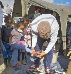  ??  ?? A CHILD is fitted with shoes, donated to SAUnite for the community.