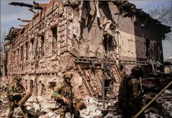  ?? Chris McGrath / Getty Images ?? Members of the Ukrainian military on Saturday walk amid debris after a shopping center and surroundin­g buildings were hit by a Russian missile strike in Kharkiv, Ukraine.