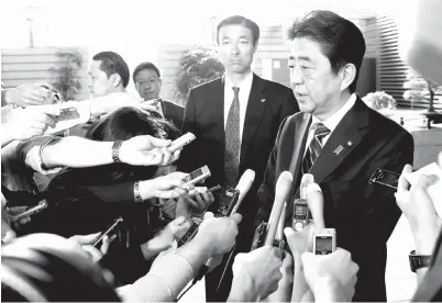  ?? — Gambar Reuters ?? ABE bercakap kepada para wartawan sejurus tiba di pejabatnya di Tokyo, semalam.