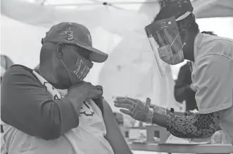  ?? DRAKE PRESTO/ THE REPUBLIC ?? Roderick Lasley, 72, raises his sleeve for pharmacist Onyi Ibeji to receive the COVID-19 vaccine at Cortez Park in Phoenix.