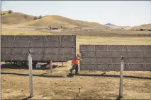  ?? ANDREW BURTON / THE NEW YORK TIMES ?? A worker walks through a solar farm near Cholame, Calif. The California Energy Commission this week approved changes to the state’s building code that will require solar panels on all new homes by 2020, putting the state even further in the forefront in the use of solar power.