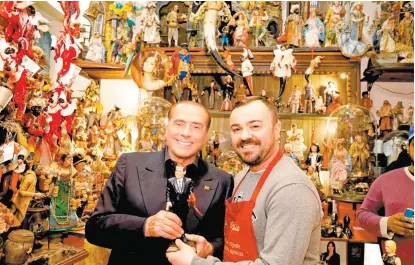  ??  ?? El jefe del partido Forza Italia sostiene una figura que lo representa en un local de artesanías en Nápoles.