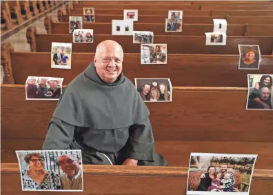  ??  ?? The Rev. Lawrence Zurek, rector at the Basilica of Saint Josaphat, sits among photograph­s of parishione­rs. He has asked parishione­rs to send photos so he has them to look at on Easter Sunday when he celebrates Mass.