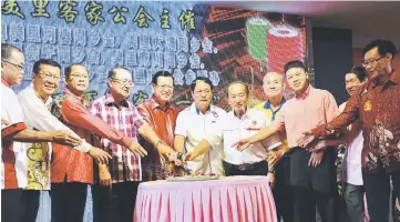  ??  ?? Lee (centre) cuts a mooncake with exco members of Miri Hakka Associatio­n