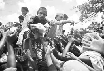  ??  ?? Rohingya refugees from Myanmar gather around a truck delivering food aid in Ukhia, Bangladesh. — AFP photo