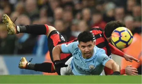  ?? OLI SCARFF/AFP/GETTY IMAGES ?? Manchester City’s Sergio Aguero, who scored twice, eyes the ball after a scramble with Bournemout­h’s Adam Smith on Saturday at Etihad Stadium.