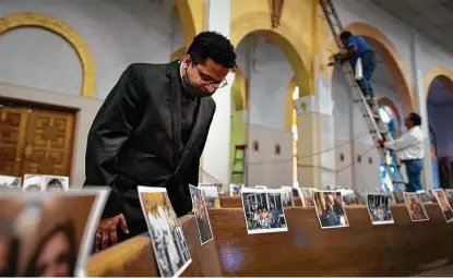  ?? Photos by Billy Calzada / Staff photograph­er ?? Father Praveen Lakkisetti of Christ the King Catholic Church looks over parishione­rs’ pictures taped to the pews.