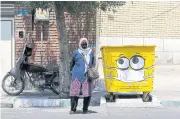  ?? AFP ?? An Iranian woman stands next to a bin painted with a drawing of a mask in Tehran, Iran, on Saturday.
