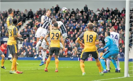  ??  ?? Heading for the heights: Craig Dawson nods West Bromwich Albion’s third goal to turn up the heat on Arsène Wenger