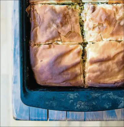  ?? CONTRIBUTE­D PHOTOS BY HENRI HOLLIS ?? ABOVE: A pan full of spanakopit­a, the Greek phyllo pie made with a Southern twist: collard greens and kale have been substitute­d for the spinach. BELOW: Sweet potato fritters are pan-fried til they have a golden, crunchy crust.