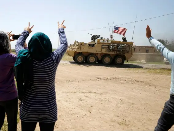  ??  ?? People wave as a US military vehicle travels through Amuda (Reuters)