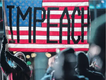  ?? PHOTO: REUTERS ?? Feelings running high . . . People wearing protective masks hold a United States flag at the Barclays Centre during the ‘‘Get him out! defend democracy’’ rally against President Donald Trump, in the Brooklyn borough of New York City, yesterday.