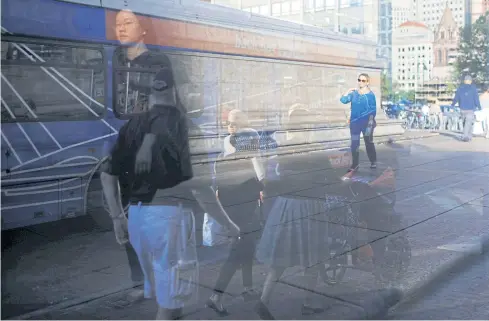  ?? REUTERS ?? Pedestrian­s are seen through a glass-enclosed bus stop in Boston. As one of the more than 30 biggest cities in America which implement energy-efficiency programmes, Boston plans to increase public transit use by 30%.