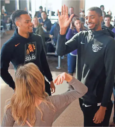  ??  ?? Elie Okobo, left, and Mikal Bridges greet a fan at a Suns and Southwest “trading places” event.