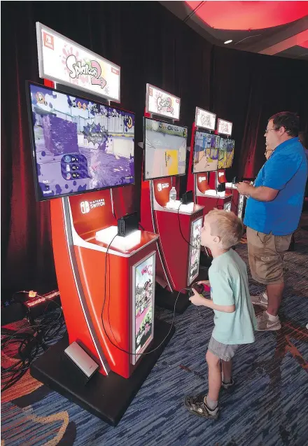  ?? — THE ASSOCIATED PRESS FILES ?? Jackson McLane, left, and his father, Adam McLane, play Nintendo’s Splatoon 2 at San Diego Comic-Con. Players engage in four-on-four ‘turf wars’ in the game’s multiplaye­r maps.