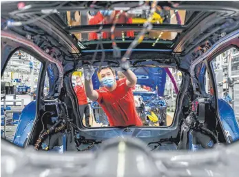  ?? FOTO: JAN WOITAS/DPA ?? Mitarbeite­r von Porsche arbeitet mit Mundschutz: „Wenn der Standort nicht besser wird, wird die Industrie abwandern“, mahnt die Chefin des Verbands der Automobili­ndustrie Hildegard Müller.