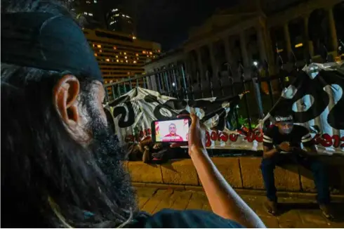  ?? Photo
AFP/VNA ?? A protester in Colombo watches an address to the nation by Sri Lanka's President Gotabaya Rajapaksa near the president's office.