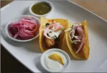  ??  ?? Baja-style Fish Tacos with lemon crema and pickled red onion.