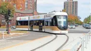  ?? MIKE DE SISTI / MILWAUKEE JOURNAL SENTINEL ?? The Milwaukee streetcar, The Hop, turns onto East Kilbourn Avenue near Cathedral Square. Local officials and the media took a preview ride on the The Hop on Monday.