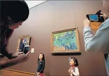  ?? Luis Sinco Los Angeles Times ?? CHINESE TOURISTS pose for pictures near a Van Gogh painting during a visit to the Getty Center in Brentwood in February.