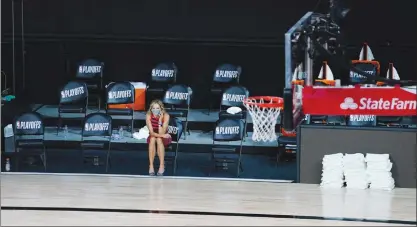  ?? The Associated Press ?? A reporter sits beside an empty court after the Milwaukee Bucks- Orlando Magic NBA playoff game was postponed. The Bucks didn't take the floor in a protest against racial injustice and the shooting of Jacob Blake, a Black man, by police in Kenosha, Wisconsin.