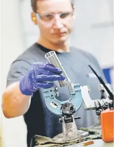  ?? – Reuters photo ?? A worker holds a component for a Volvo truck at the Muller manufactur­ing facility in Redditch, Britain.