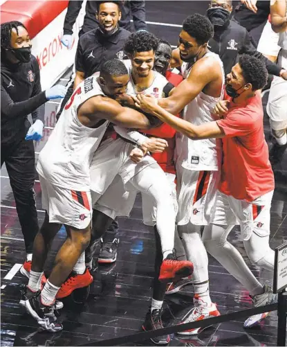  ?? DENIS POROY ?? Trey Pulliam is mobbed by teammates after hitting a running bank shot at the buzzer Saturday to lift the Aztecs over Nevada.