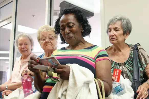  ?? CITIZEN NEWS SERVICE PHOTO FLOOR FLURIJ ?? Florence Lee, 82, centre, looks at pictures of her friend’s grandchild­ren outside of their weekly yoga class.