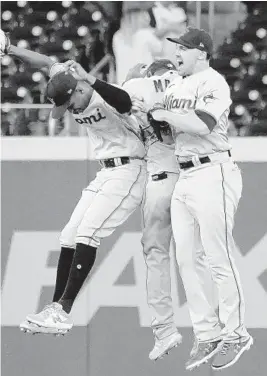  ?? JOHN BAZEMORE/AP ?? Marlins outfielder­s Corey Dickerson, from left, Starling Marte, and Adam Duvall celebrate after defeating the Braves on Monday in Atlanta.