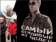  ?? AP/DMITRY LOVETSKY ?? Women pass a kiosk Wednesday in St. Petersburg, Russia, displaying a T-shirt bearing the likeness of Russian President Vladimir Putin. The shirt’s slogan reads: “The most polite man.”