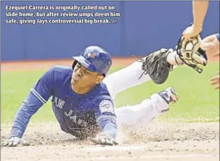  ?? AP ?? Ezequiel Carrera is originally called out on slide home, but after review umps deem him safe, giving Jays controvers­ial big break.