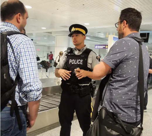  ??  ?? Le gendarme Nicolas Ferraro de la GRC distribuai­t des tracts aux touristes hier en fin de journée à l’aéroport de Montréal.