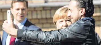  ?? Foto: Bernd von Jutrczenka, dpa ?? Der Moment, der den Syrer Rodin Saouan ins arabische Fernsehen bringt. Am 15. September 2015 drückt er auf den Auslöser seines Smartphone­s: Fertig ist das Selfie mit Kanzlerin Angela Merkel.