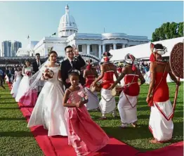  ??  ?? Pretty in pink: Flowergirl­s leading couples down a red carpet at the wedding ceremony.