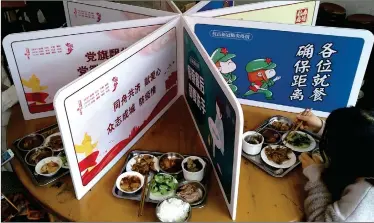  ?? Cnsphoto Photo: ?? Workers have dinner while separated by paper boards bearing antiepidem­ic slogans in the canteen of the Yanqian town government hall, East China’s Fujian Province, on Thursday. The idea is to prevent crossinfec­tions.