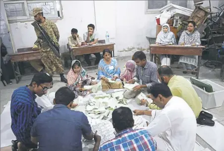  ?? Rizwan Tabassum/AFP/Getty Images ?? Pakistani election officials count paper ballots Wednesday at a polling station in Karachi. The vote-counting began after a knife-edge general election as former cricket hero Imran Khan sought power on a day marred by a bloody suicide bombing and...