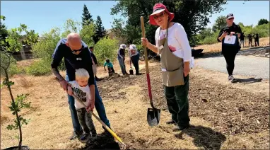  ?? RECORDER PHOTO BY ESTHER AVILA ?? As Cathy Capone, right, watches and offers instructio­n, Phillip Duncan helps his 4 year old grandson K’ehleb prepare the site for the planting of a Valley Oak tree on Friday in recognitio­n of Arbor Day at the Tule River Parkway.