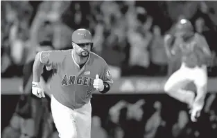  ?? MARK J. TERRILL/THE ASSOCIATED PRESS ?? ABOVE: The Angels’ Albert Pujols runs to first base Saturday after hitting a grand slam, his 600th homer of his career, while Ben Revere jumps in the background during a game against the Twins in Anaheim, Calif. The Angels won, 7-2.